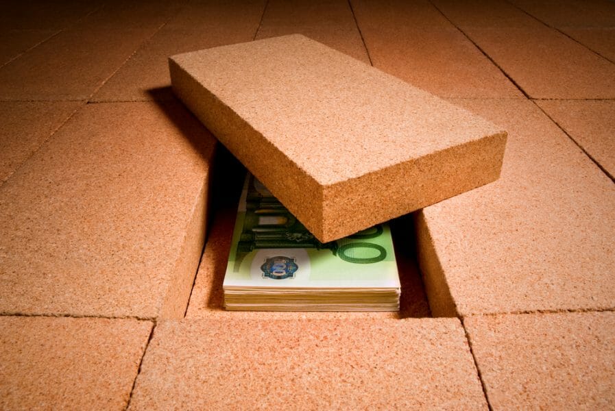 Brick walkway with one brick removed, revealing pile of money hidden under it.