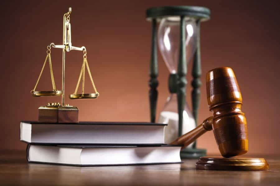 law books with scales of justice, gavel, and sands of time timer.