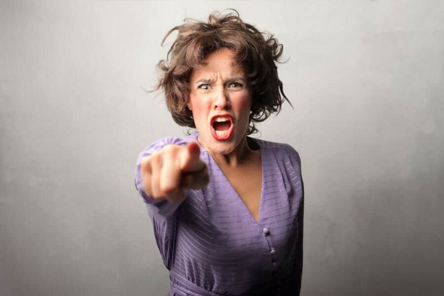 Angry screaming woman pointing directly at the camera.