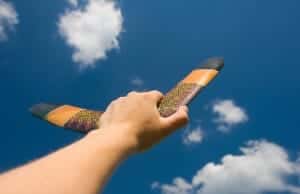 Hand holding a boomerang up to the sky