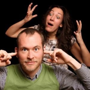 Woman arguing with a man who is staring forward with his fingers in his ears.