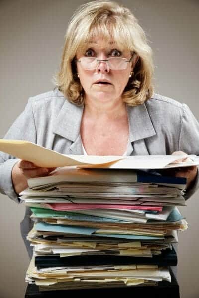 Harried woman holding a large stack of paperwork.