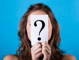 woman holding a paper with a question mark in front of her face.