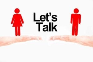 Hands holding red figures of a man and a woman with the words "Let's talk" between them.