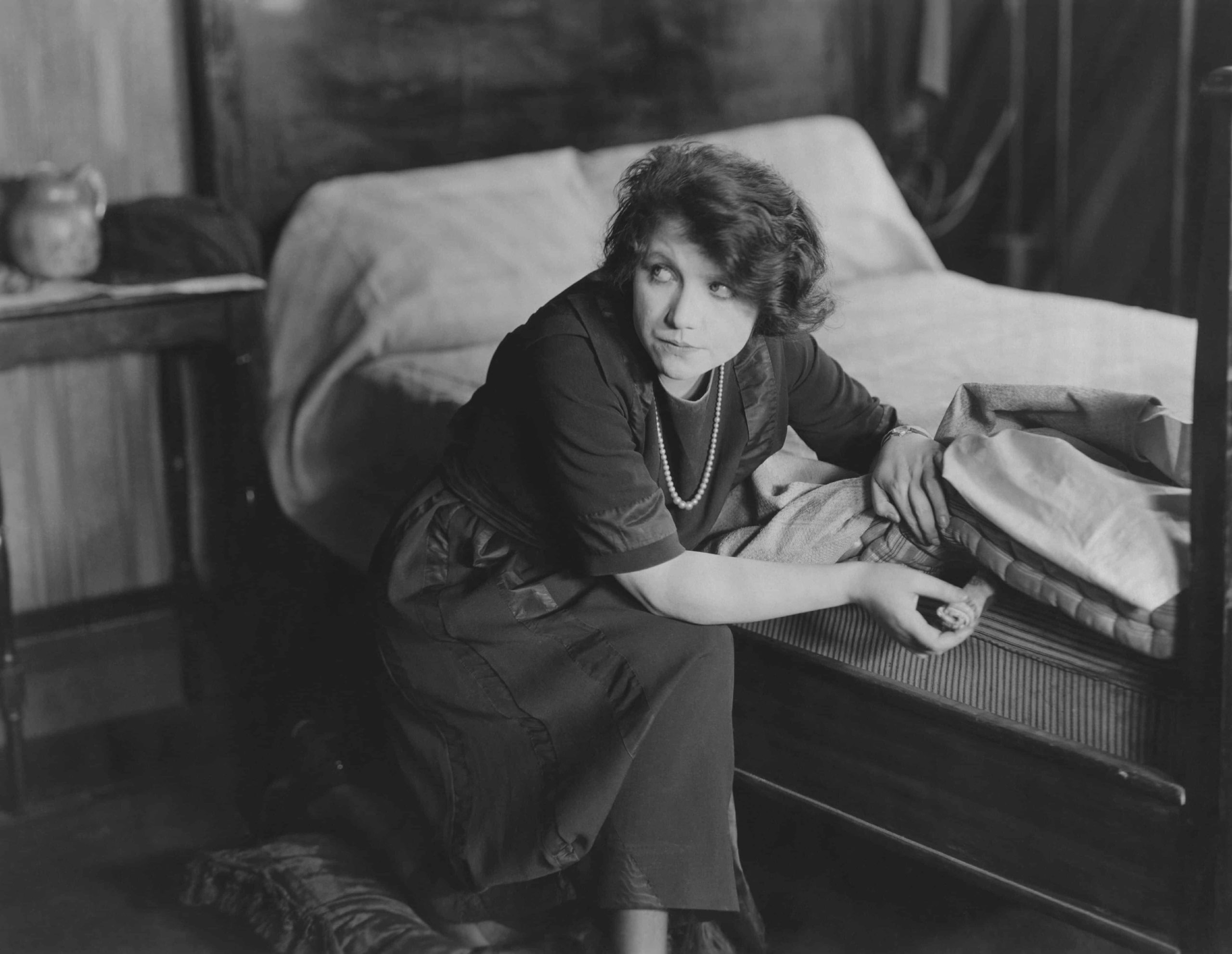 Old black and white picture of a woman in the 1920s hiding money under the mattress.