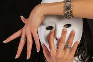 Woman hiding behind white mask with hands around her face.