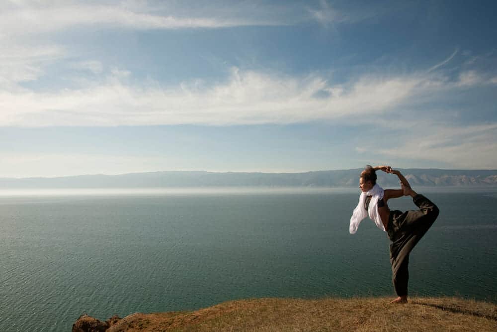 Beautiful woman doing a yoga pose in front of the ocean.