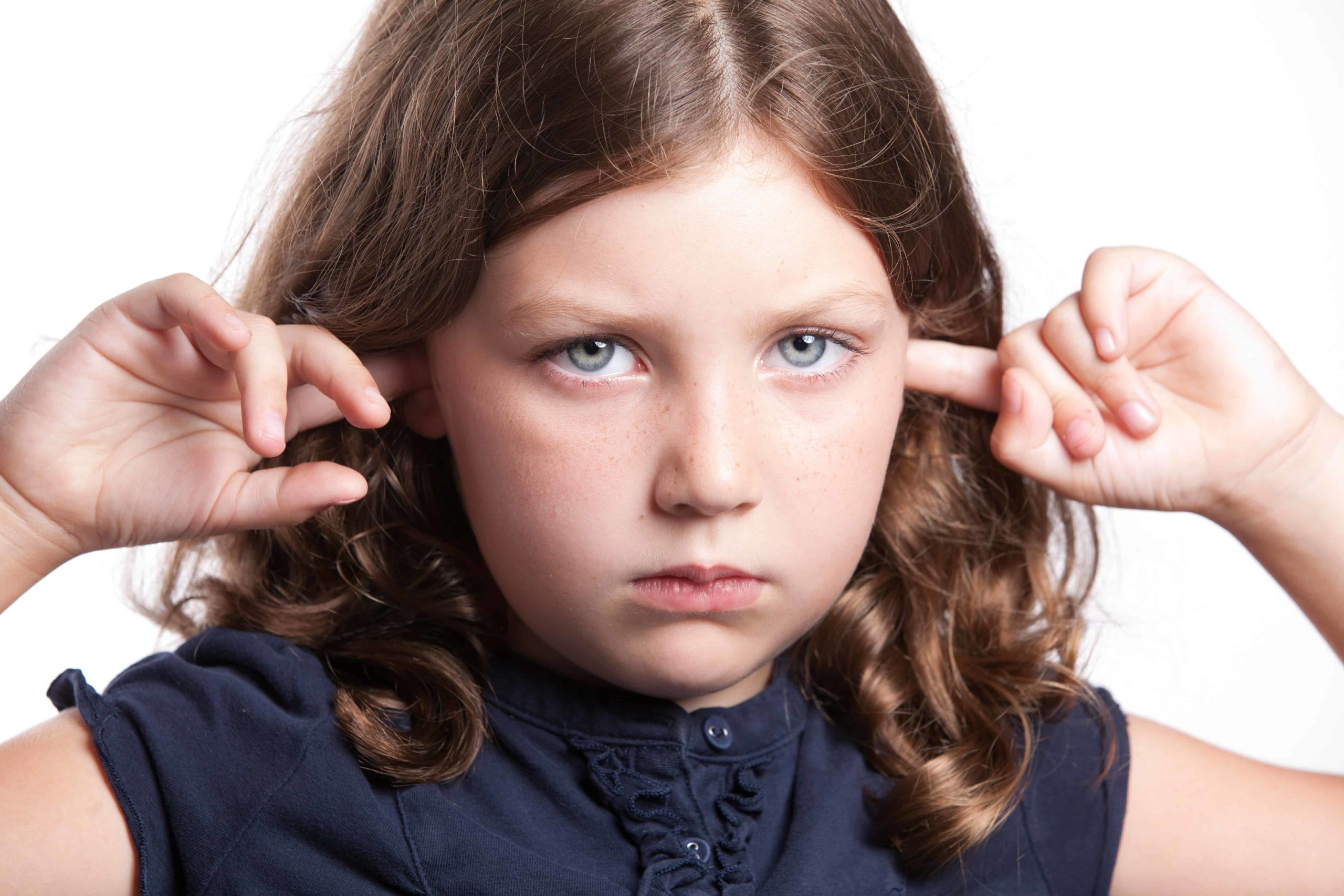 Small sad girl with her fingers in her ears.