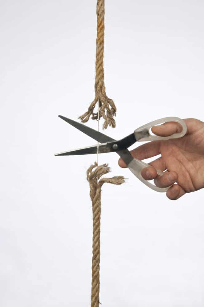 Hand cutting a rope with scissors.