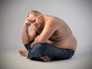 Obese man holding his head and looking depressed
