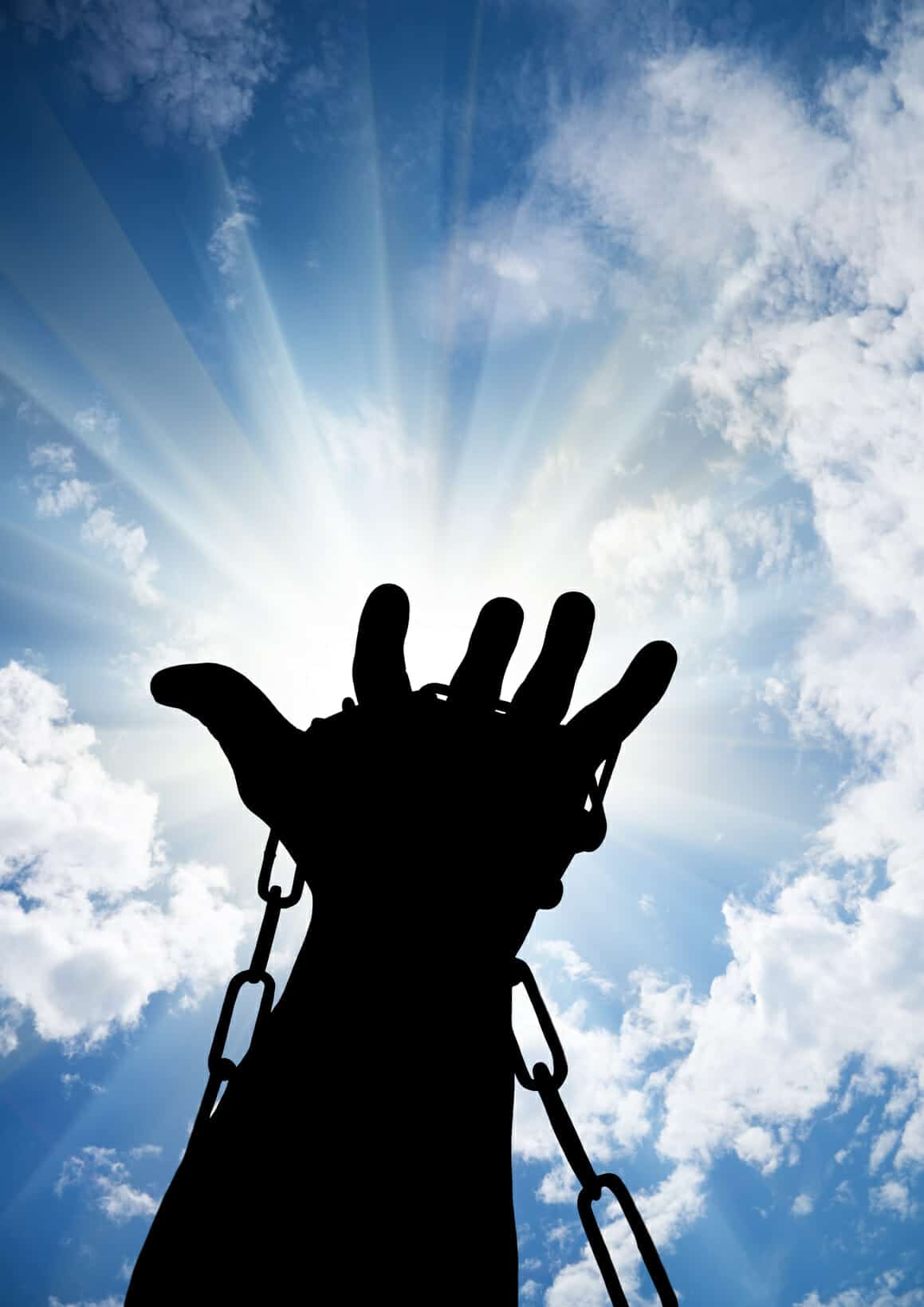 Hands tied up with chains against blue sky