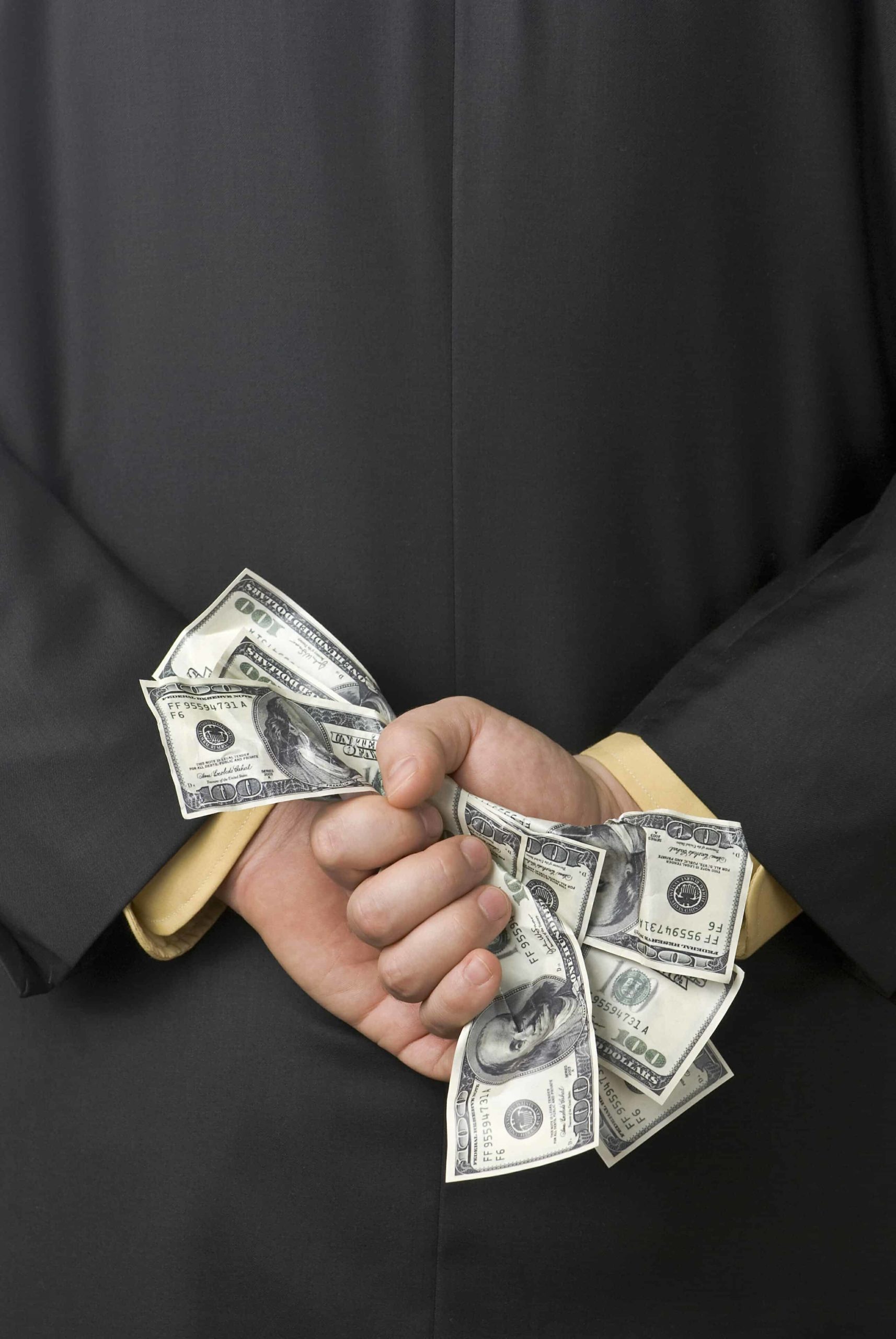 Man holding 100 dollar bills behind his back.