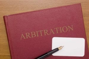 Red book with the word "Arbitration" on it with a blank business card and a pen.