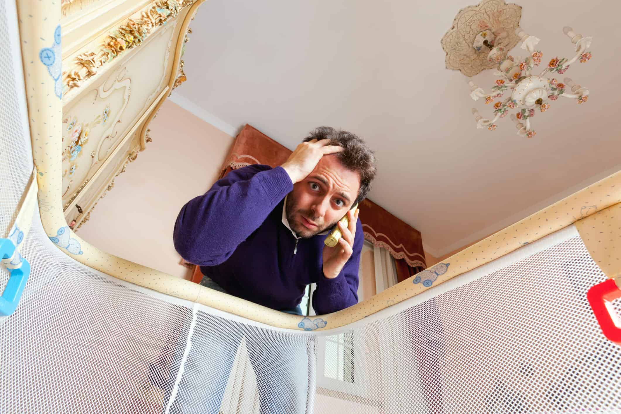 Anxious father on the phone looking into play pen.