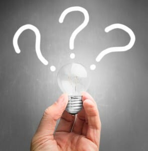 Hand holding light bulb with question 3 question marks on top of it.