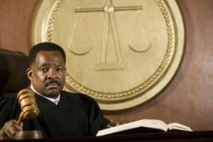 Stern judge reading a law book and banging his gavel in divorce court.