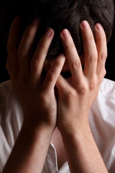 Grieving person holding hands over face.