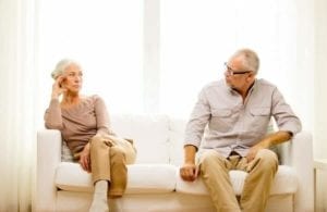 Senior couple, aggravated with each other, sitting on a couch. Grey Divorce.