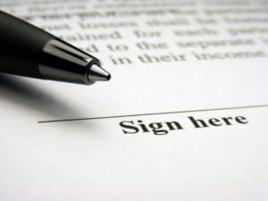 Pen sitting next to signature line on legal documents