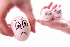 One upset egg with a face next to happy egg couple. Divorce