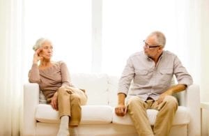 Crabby senior couple on a couch contemplating gray divorce.