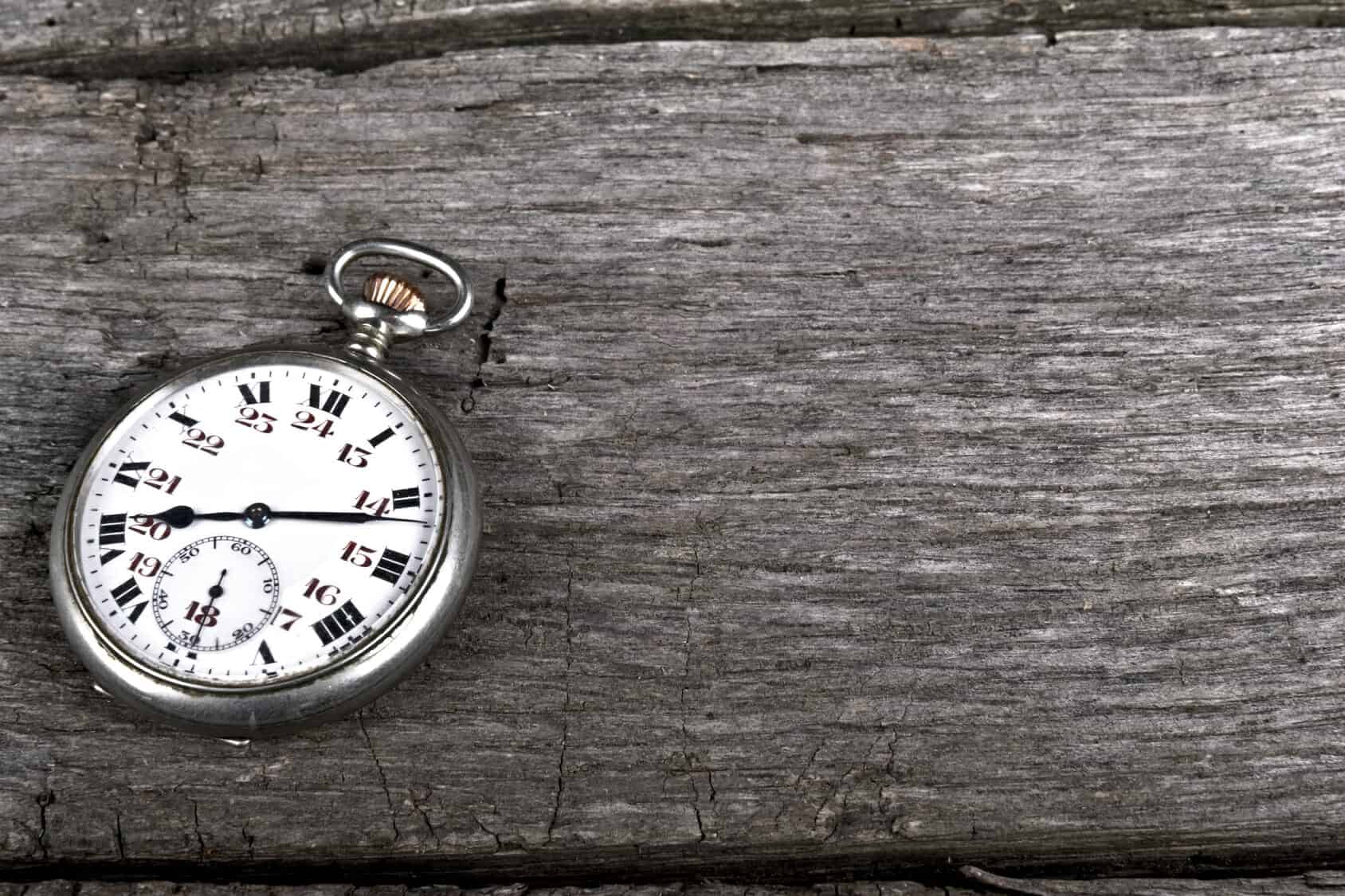 Vintage pocket watch on old wood shows passage of time.
