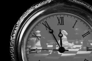Pocket watch with chess pieces on board check mate