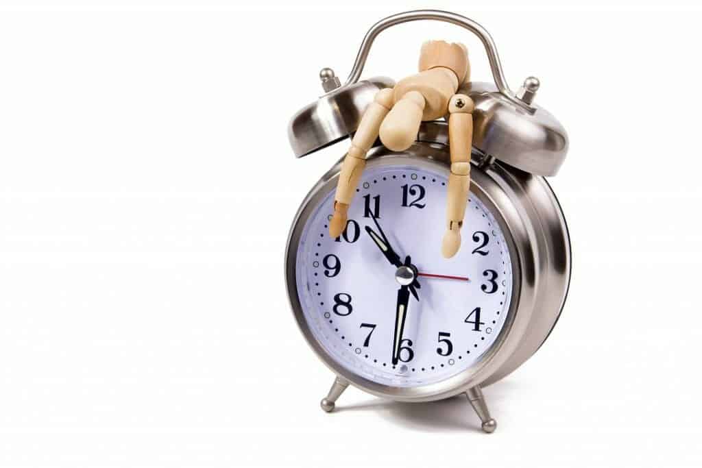 Exhausted wooden figure draped over a clock signifying time to divorce.