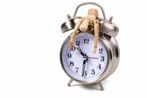 Exhausted wooden figure draped over a clock signifying time to divorce.