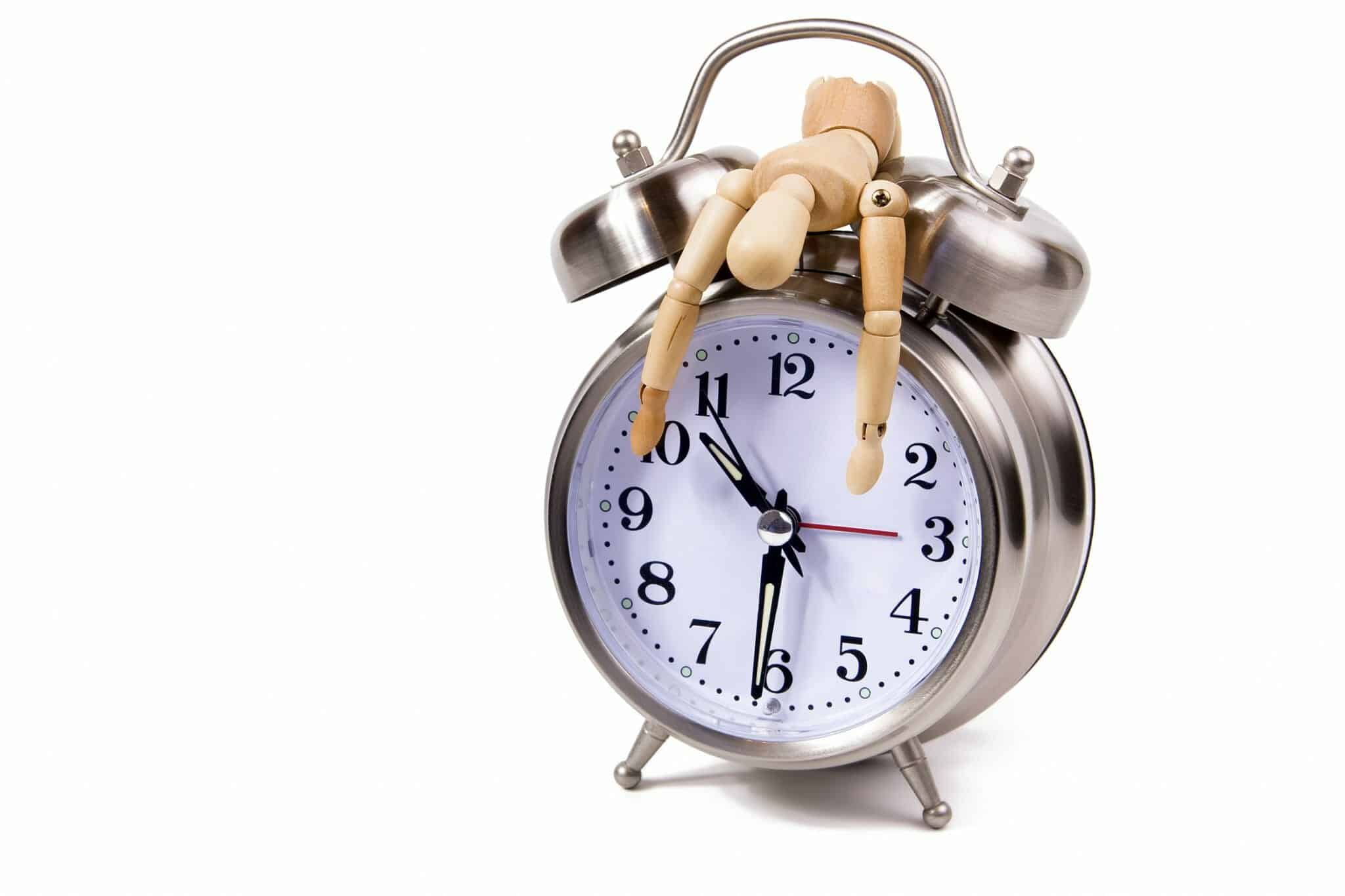Exhausted wooden figure draped over a clock signifying time to divorce.