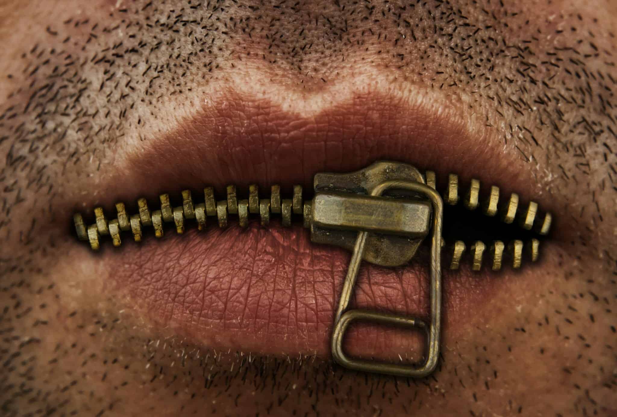 Close up of lips being zipped with a zipper.