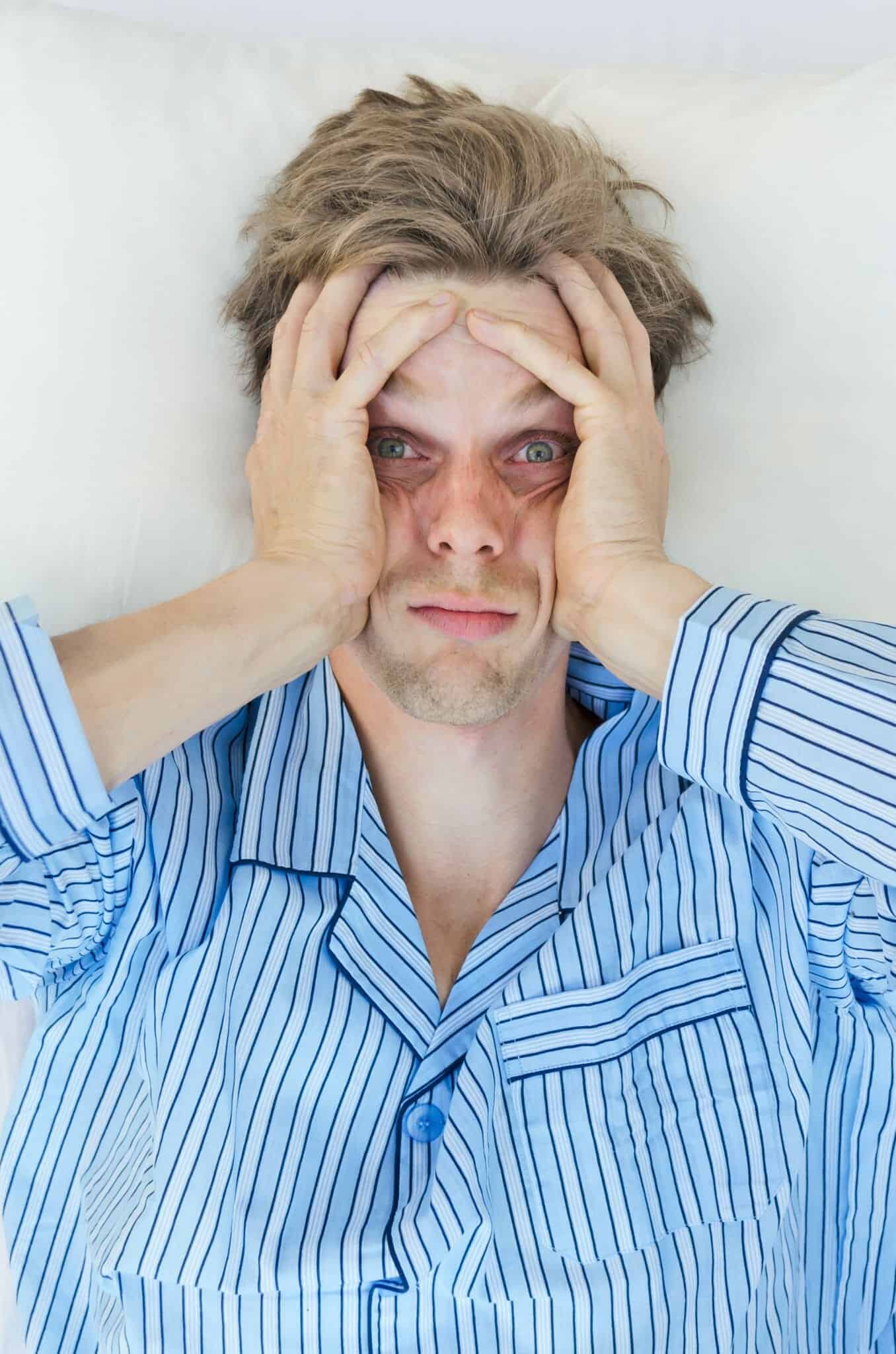 Exhuasted man in bed with his eyes open - can't sleep!