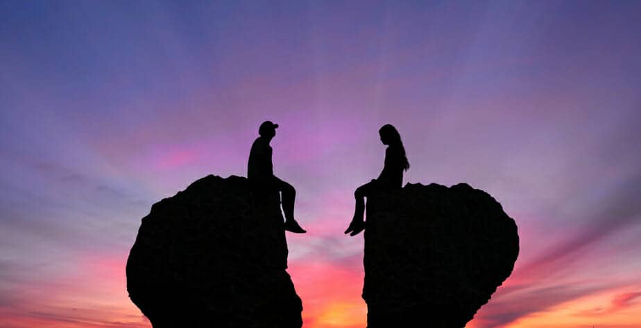 Divorcing sitting on rocks shaped as broken heart signifying amicable divorce.