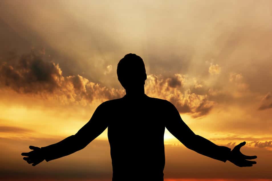 Silhouette of a man practicing gratitude in the sunrise.