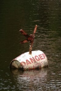 Explosive barrel symbolizing the dangers of a cheap divorce floating in water with "Danger" painted on the barrel
