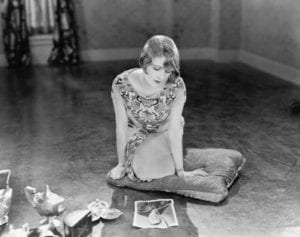 Black and white 1920s woman who can't let go staring at torn picture of her man.