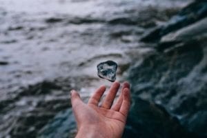 Hand letting go of a stone into water.