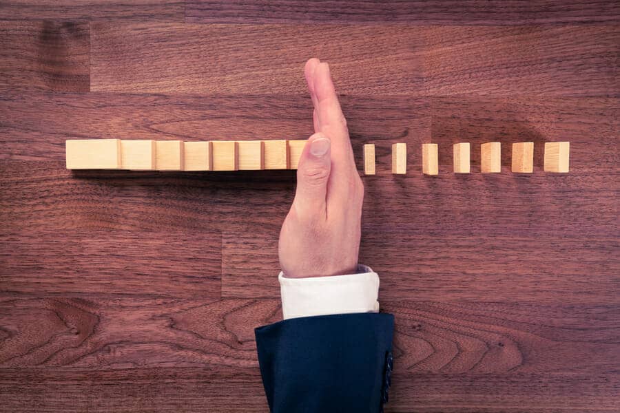 Hand stopping a line of dominoes. Divorce strategies to stop the damage.
