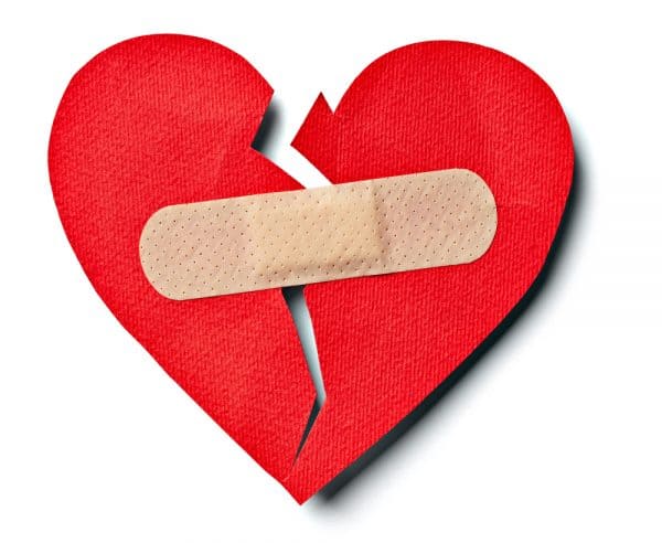 Broken red paper heart with a band aid on it designating reconciling with your ex