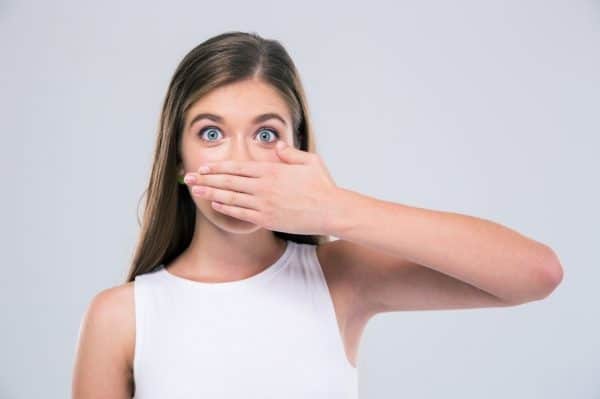 Surprised woman with hand over her mouth.
