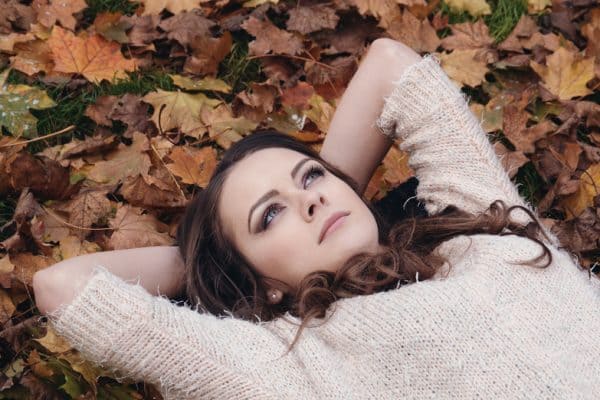 Beautiful woman laying in a pile of fall leaves wondering about the best advice for divorcing women