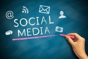 Words "social media" written on a blackboard with chalk accompanied by social media symbols