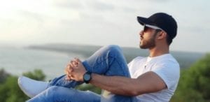 Handsome young man in baseball cap and glasses in front of a lake - free lifestyle