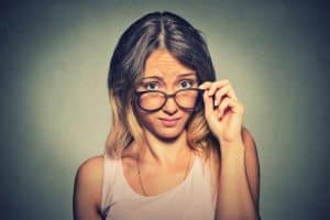 Young woman thinking about alimony in Illinois looking down over big glasses