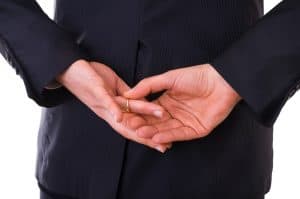 Cheating spouse wiuth hands behind his back taking off wedding ring.