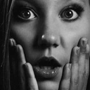 Black and white photo of a beautiful surprised woman who didn't understand the danger of a cheap divorce.