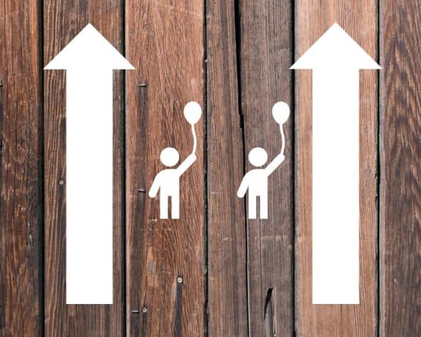 Wooden boards with two parallel arrows with icons of kids in between them to signify parallel parenting.