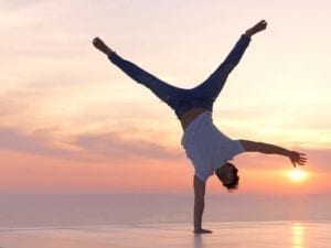 Man celebrating his divorce doing a one armed hanstand in the sunset.