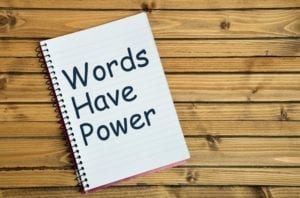 Spiral notebook with "Words Have Power" written on it on wooden background, signifying that divorce terms are important.