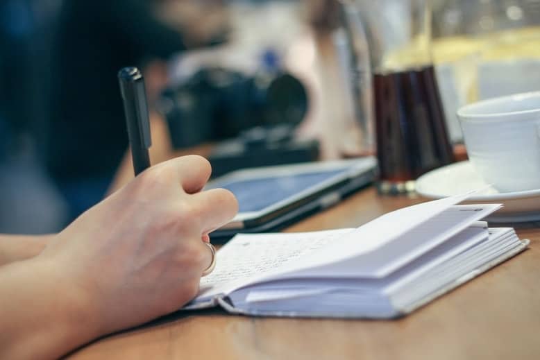 Woman's hand writing in a journal that she's keeping while co-parenting during quarantine.